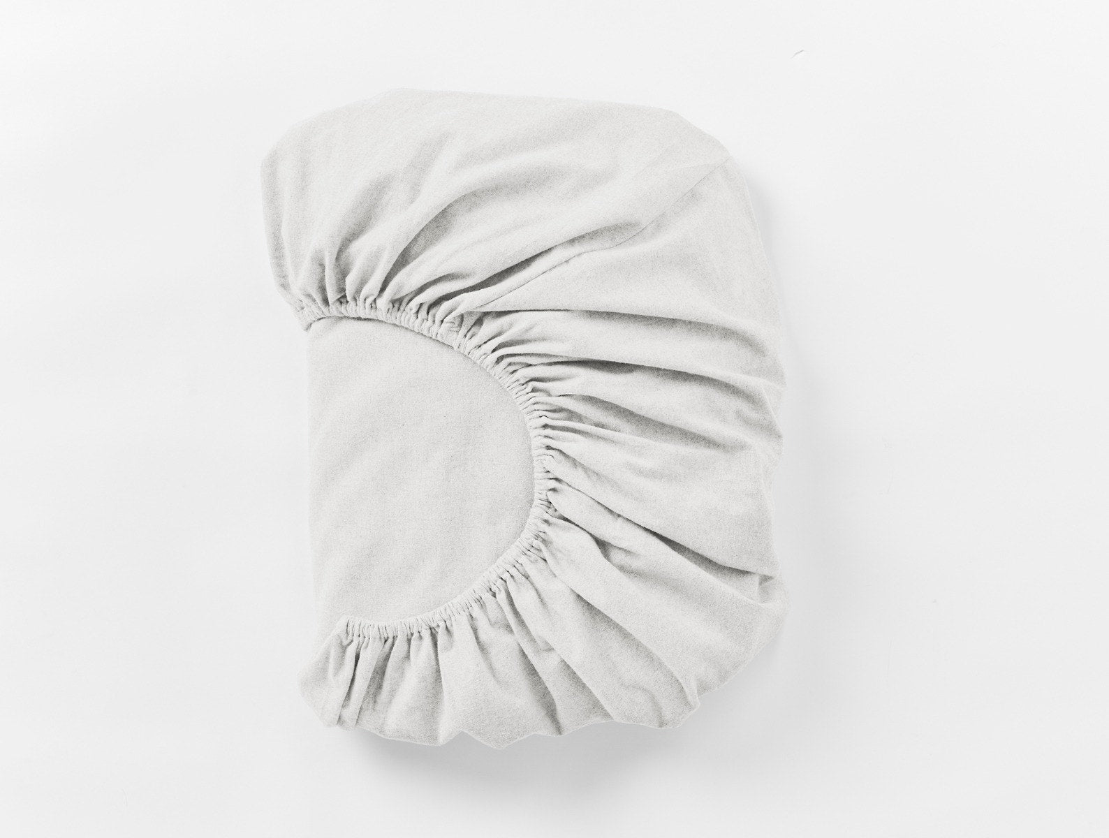 Coyuchi Cloud Brushed Organic Flannel Fitted Sheet in Alpine White – folded, displaying elastic in seam. #colour_alpine white