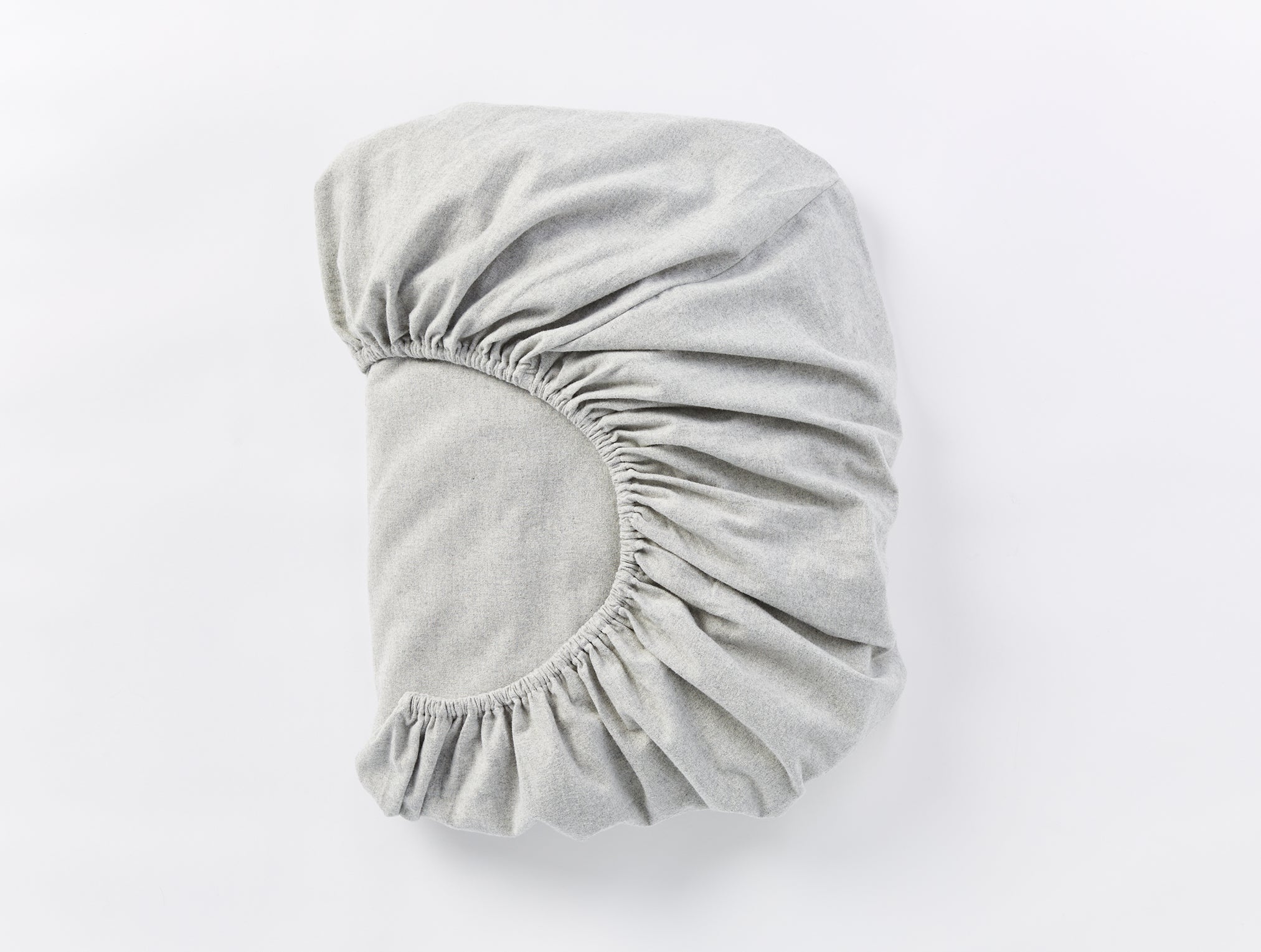Coyuchi Cloud Brushed Organic Flannel Fitted Sheet in Pale Grey Heather – folded, displaying elastic in seam. #colour_pale gray heather