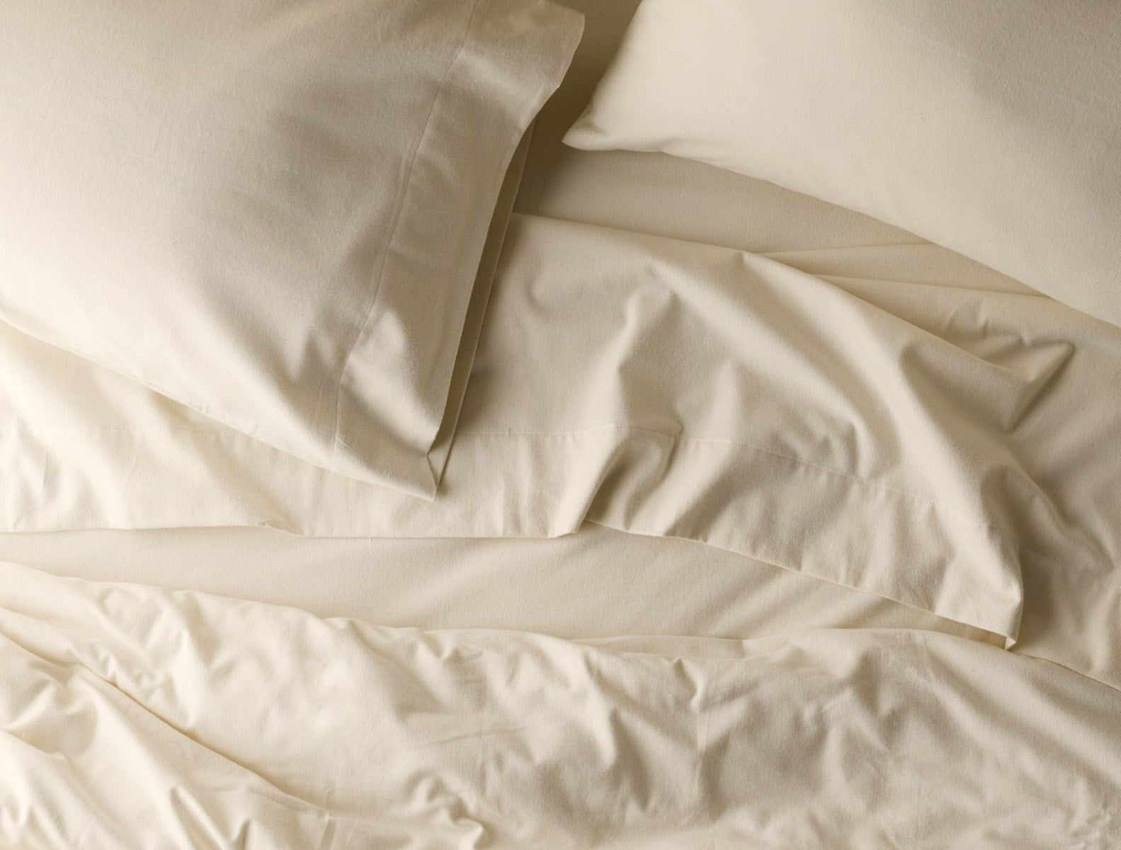 Coyuchi Cloud Brushed Organic Flannel Fitted Sheet in Undyed – folded, displaying elastic in seam. #colour_undyed