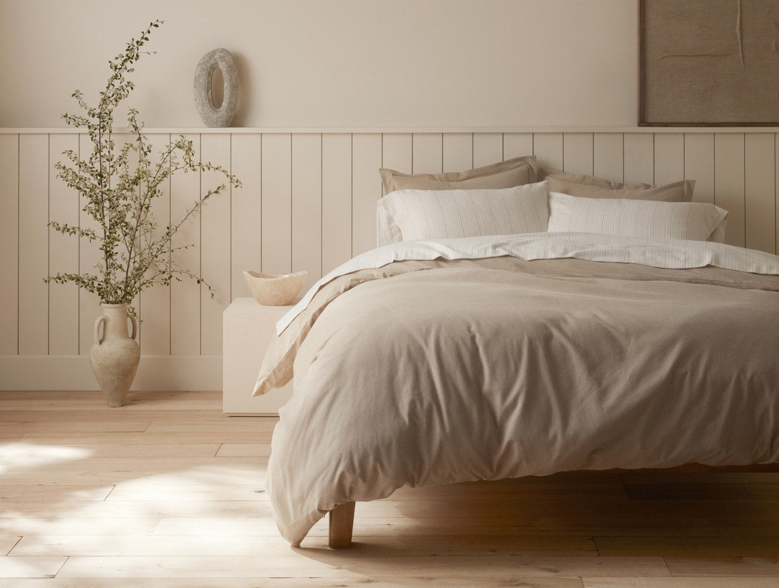 Coyuchi Cloud Brushed Organic Flannel Sheet Set in Camel Heather - made bed in neutral room showcasing colour in natural light. #colour_camel heather