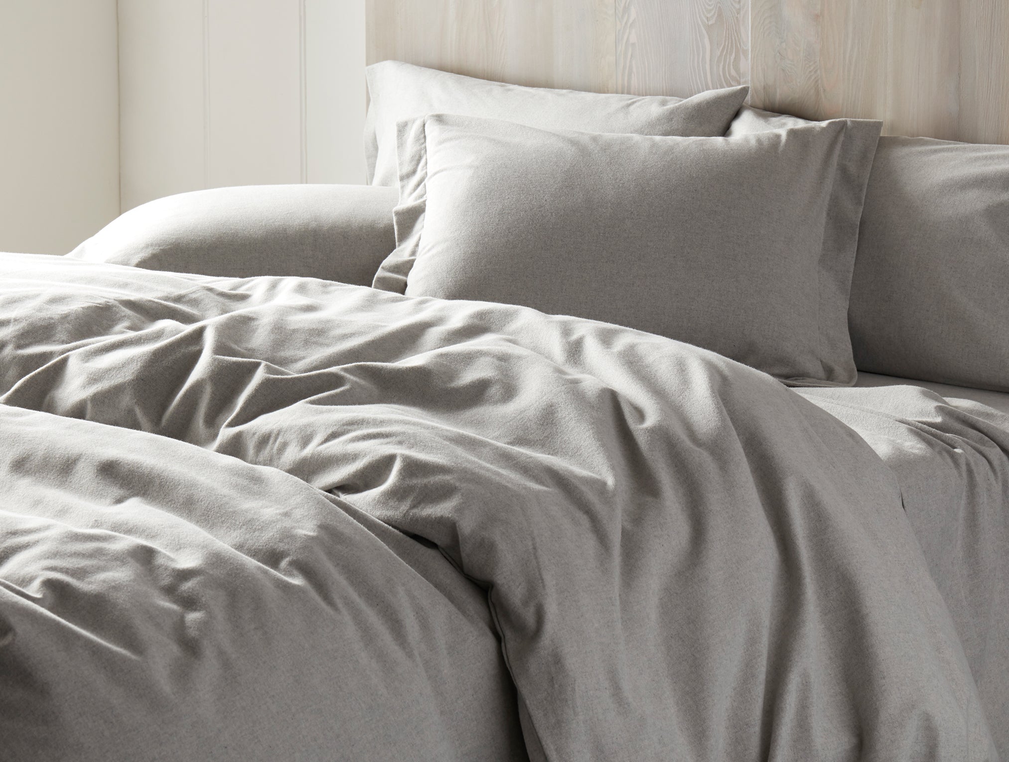 Coyuchi Cloud Brushed Organic Flannel Sheet Set in Pale Grey Heather – detail shot of made bed highlighting brushed texture. #colour_pale gray heather