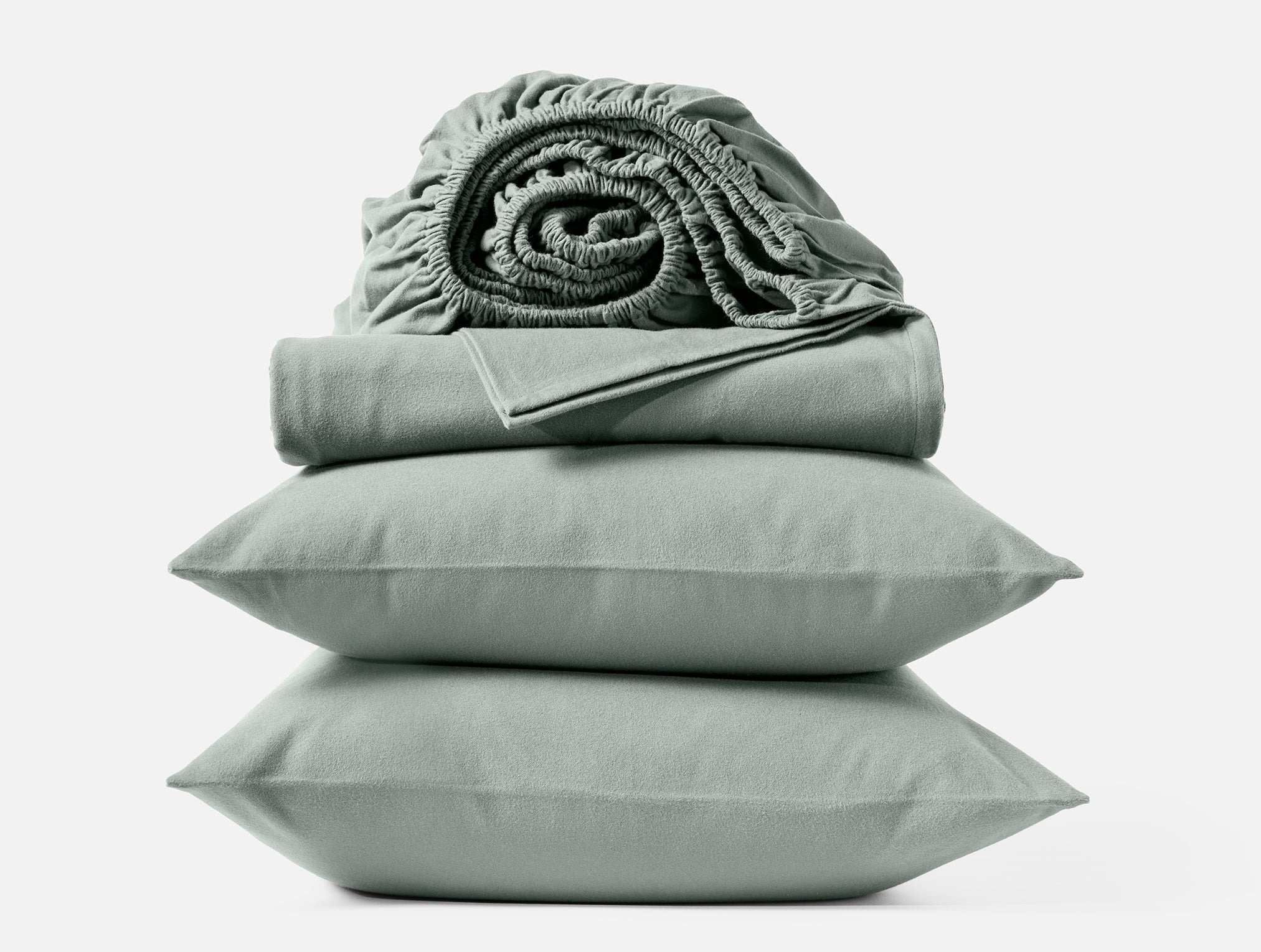 Coyuchi Cloud Brushed Organic Flannel Sheet Set in Sage – stacked display with pillows and folded sheets. #colour_sage