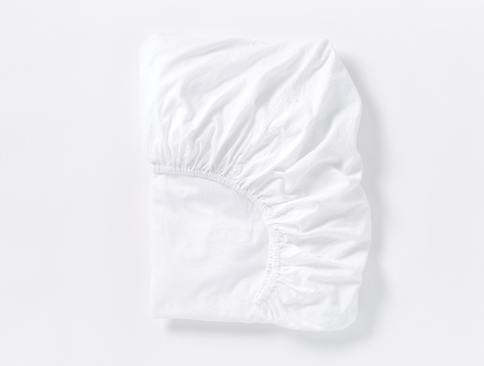 Coyuchi Cloud Soft Organic Sateen Fitted Sheet in Alpine White – folded, displaying elastic in seam. #colour_alpine white
