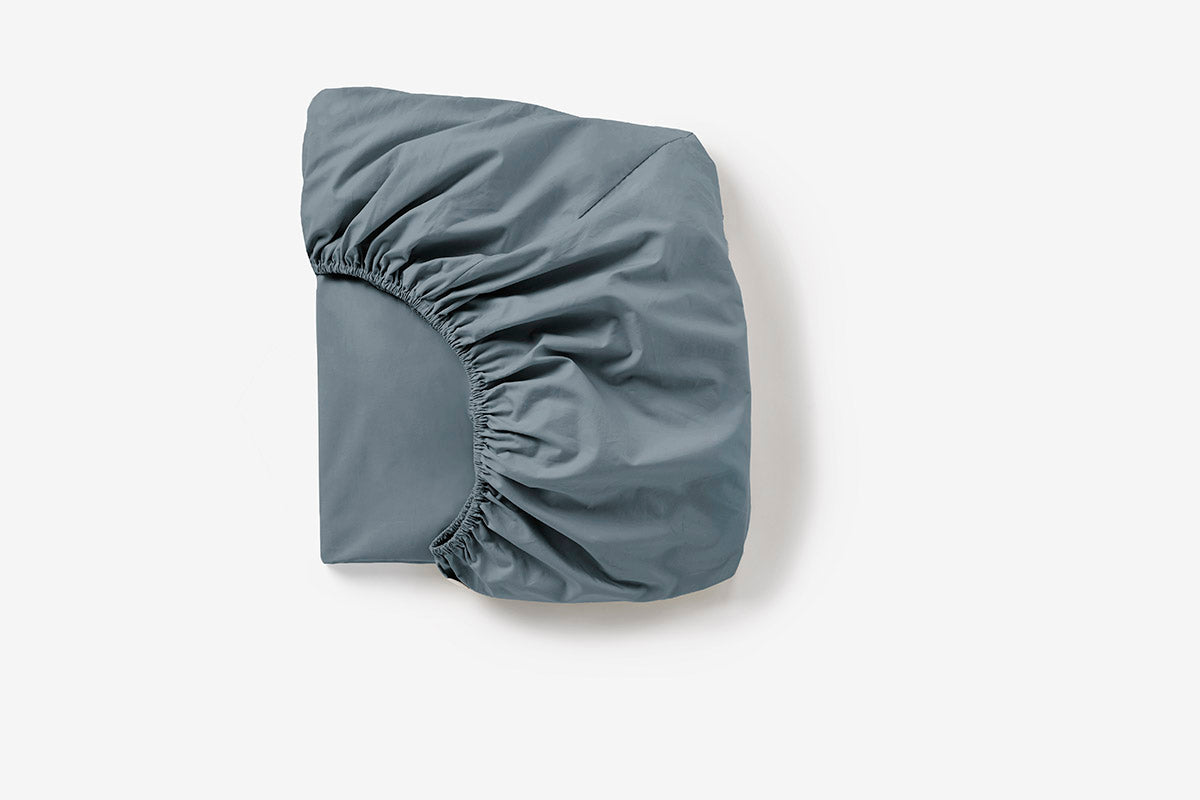 Coyuchi Cloud Soft Organic Sateen Fitted Sheet in Gulf – folded, displaying elastic in seam. #colour_gulf