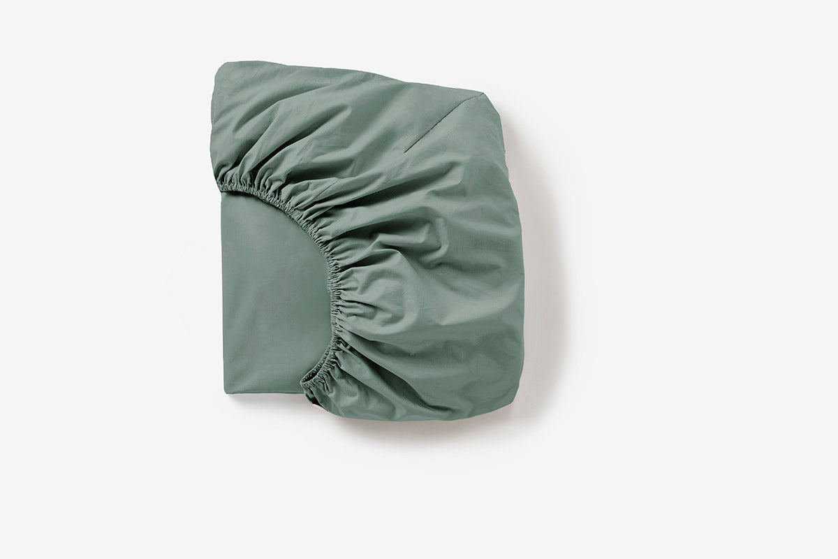 Coyuchi Cloud Soft Organic Sateen Fitted Sheet in Sage – folded, displaying elastic in seam. #colour_sage