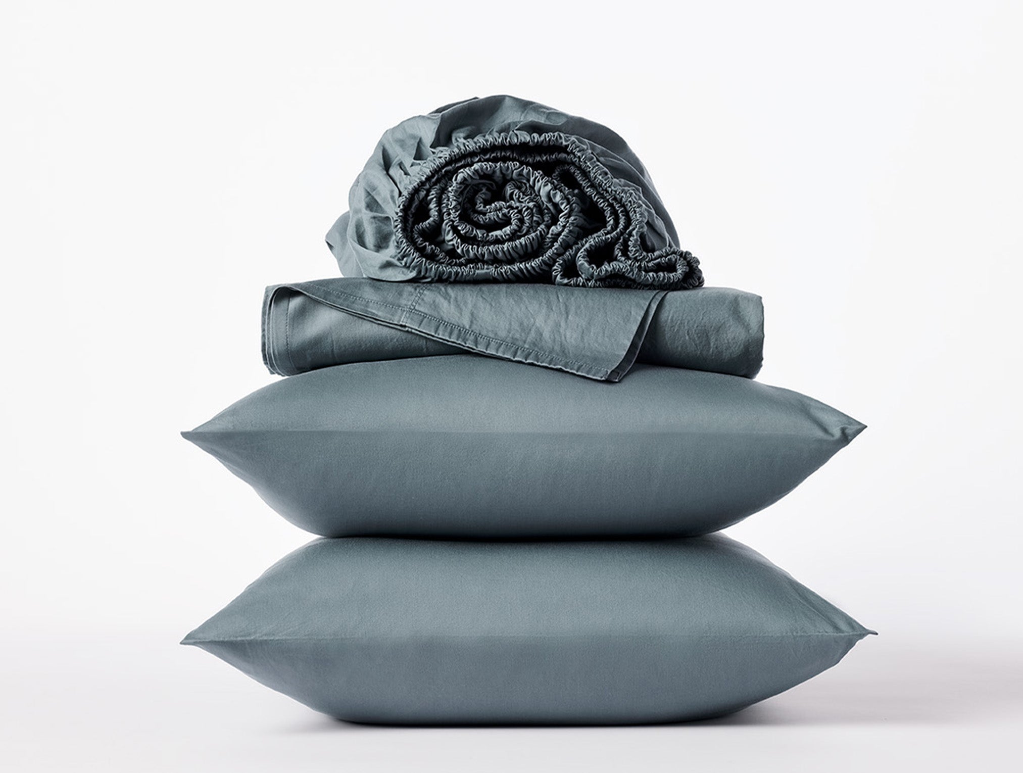 Coyuchi Cloud Soft Organic Sateen Sheet Set in Gulf – stacked display with pillows and folded sheets. #colour_gulf