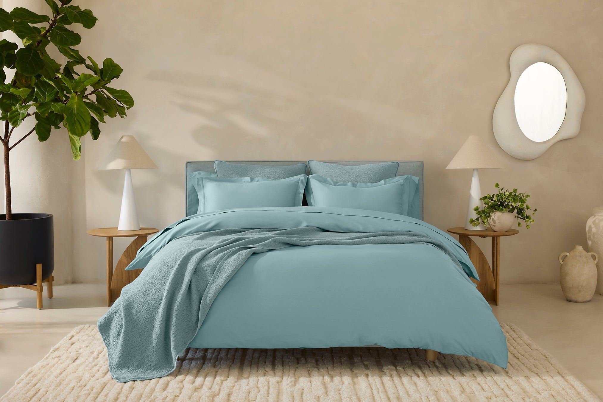 Coyuchi Cloud Soft Organic Sateen Sheet Set in Pacific Blue – styled bed showing light blue tone in a neutral coloured room. #colour_pacific blue
