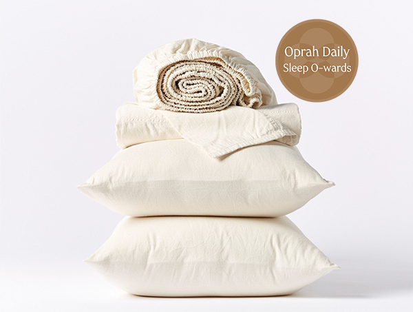 Coyuchi Cloud Soft Organic Sateen Sheet Set in Undyed – stacked display with pillows and folded sheets. #colour_none