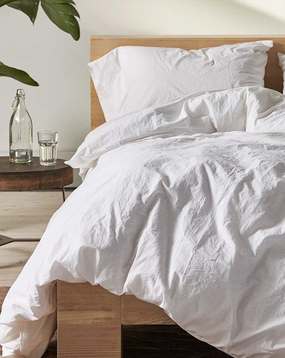 Coyuchi Organic Crinkled Percale Sheet Set in Alpine White – detail shot of made bed emphasizing relaxed texture. #colour_alpine white