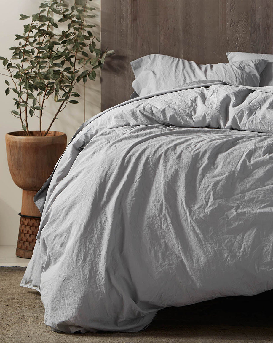 Coyuchi Organic Crinkled Percale Sheet Set in Pewter – made bed highlighting texture and colour in natural light. #colour_pewter