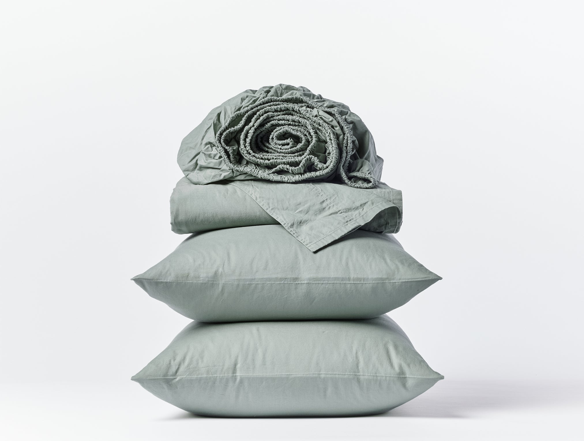 Coyuchi Organic Crinkled Percale Sheet Set in Sage – stacked display with pillows and folded sheets. #colour_sage