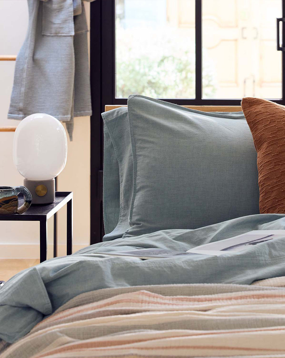 Coyuchi Organic Crinkled Percale Sheet Set in Surf Chambray – detail shot of styled bed in natural light. #colour_surf chambray