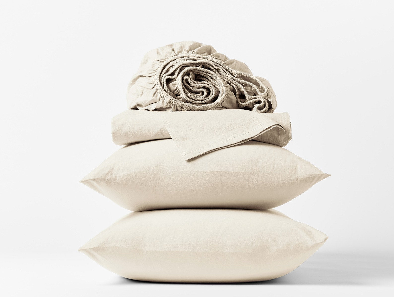 Coyuchi Organic Crinkled Percale Sheet Set in Undyed – stacked display with pillows and folded sheets. #colour_undyed