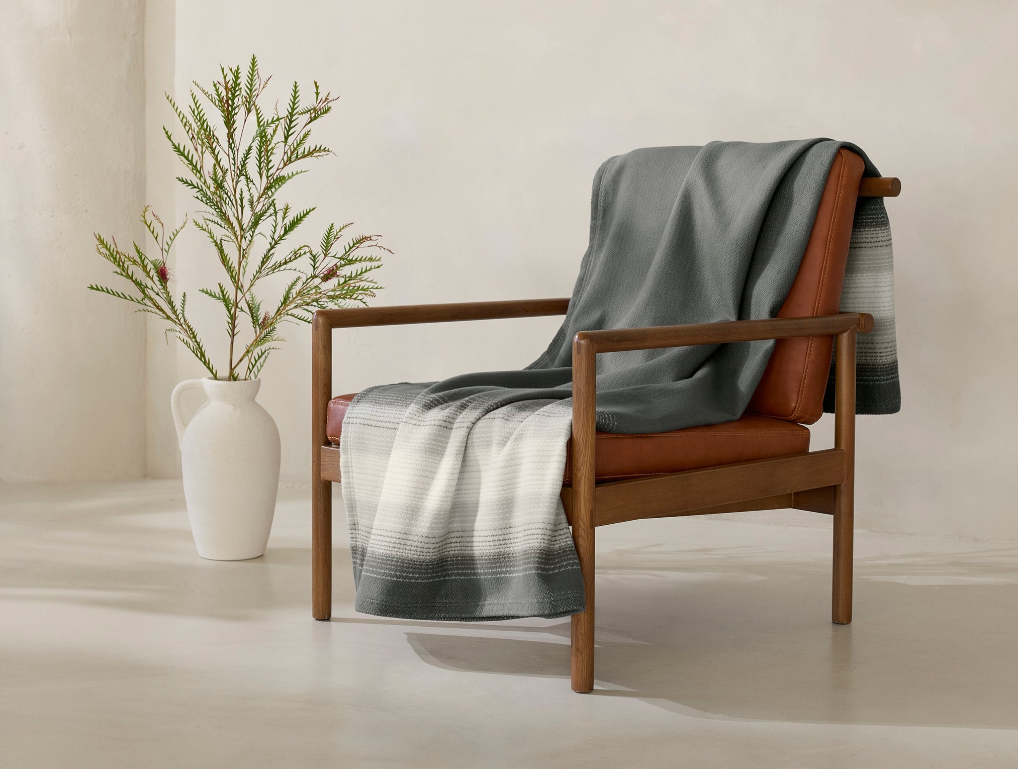 Coyuchi Horizon Supersoft Organic Throw - draped over chair with plant in corner #colour_Gray Ombre