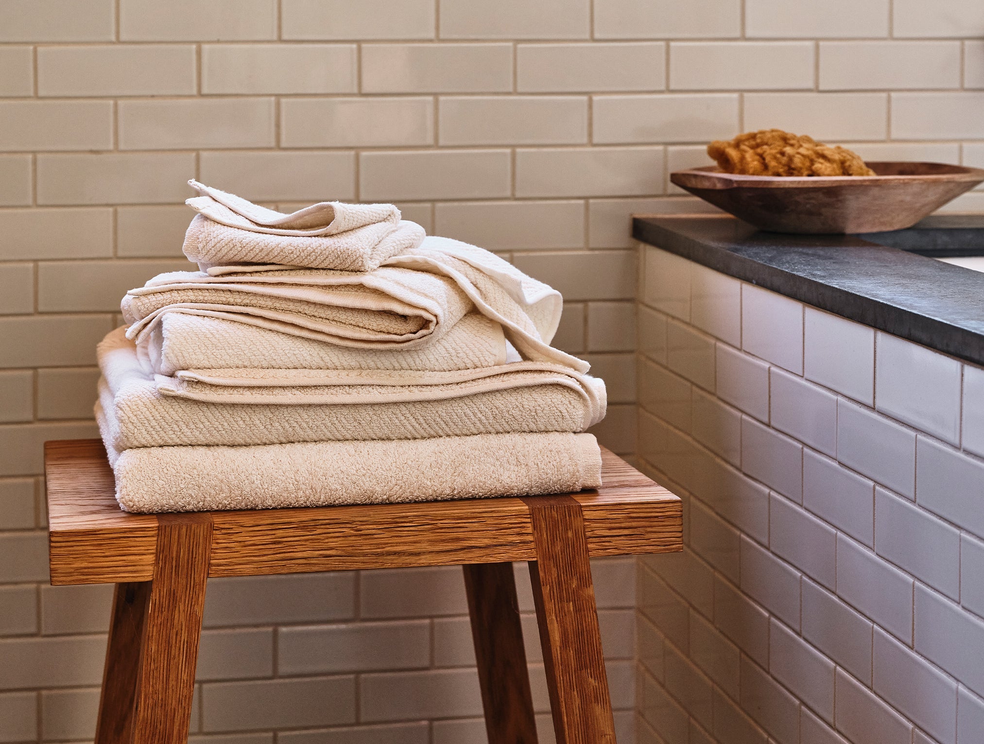 Coyuchi Organic Air Weight Towel - stacked on wood table in bathroom #color_undyed