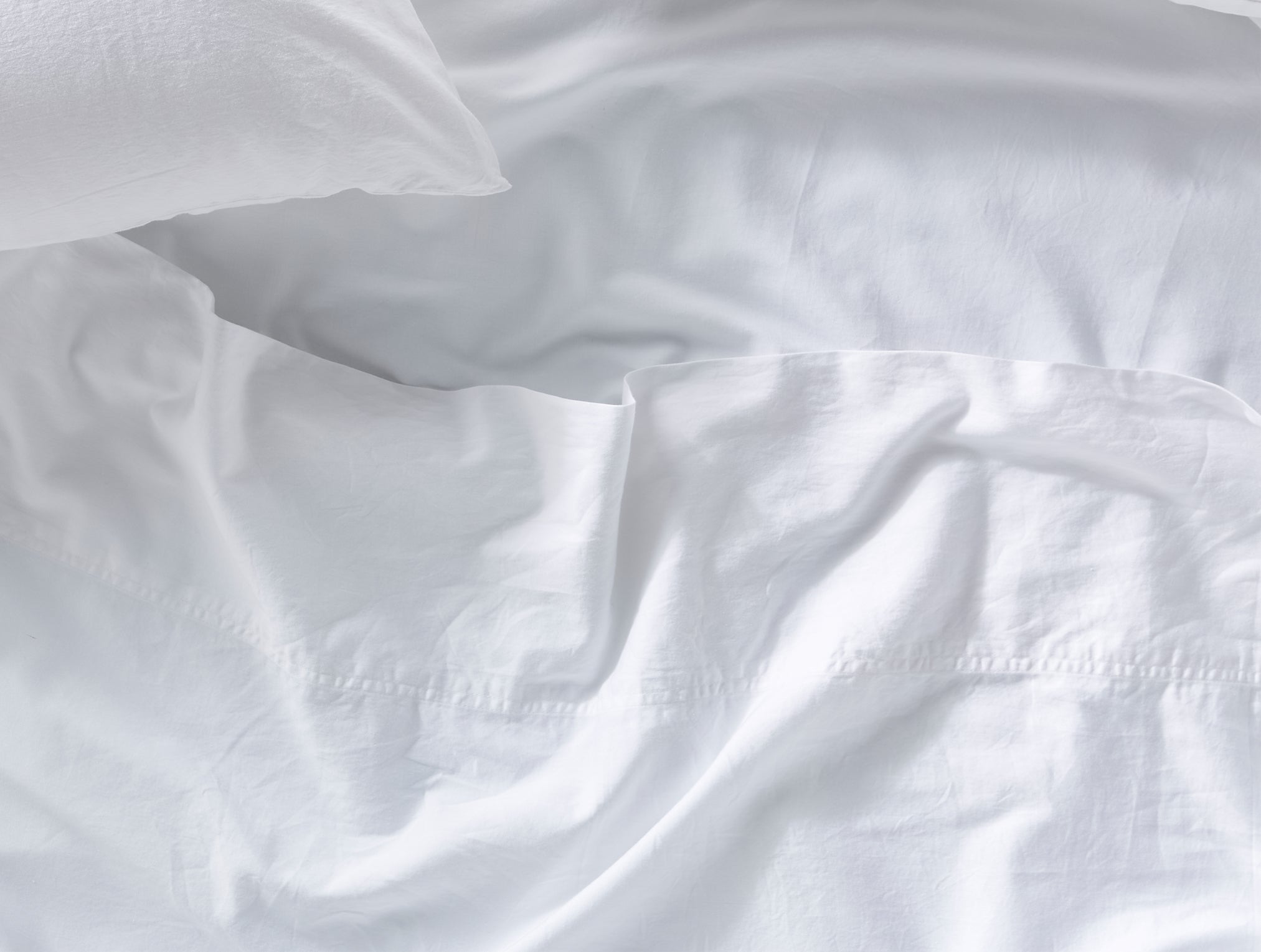 Coyuchi Organic Cloud Soft Sateen Pillowcase - close up view of matching sheets #colour_alpine white