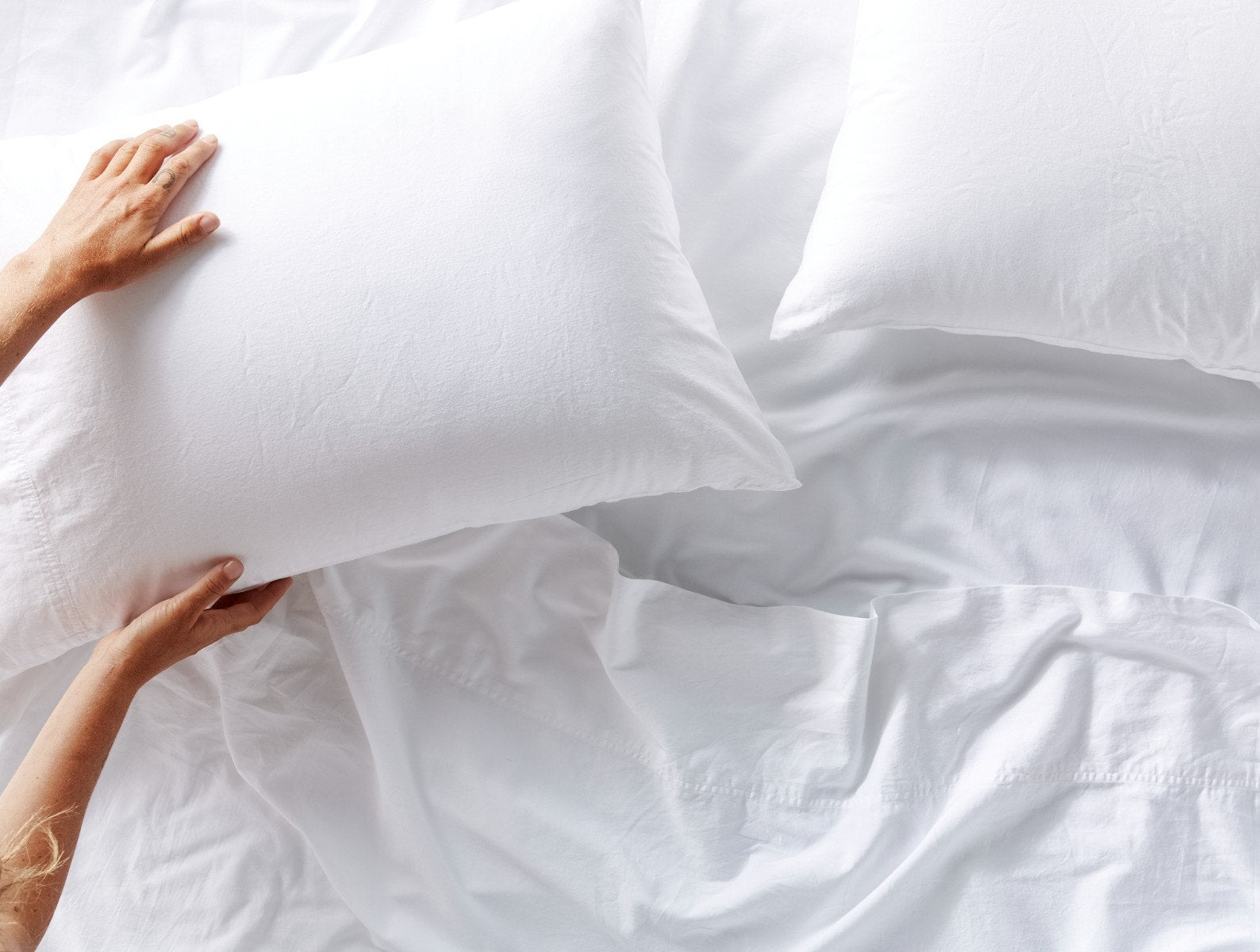 Coyuchi Organic Cloud Soft Sateen Pillowcase - model making bed matching sheets #colour_alpine white