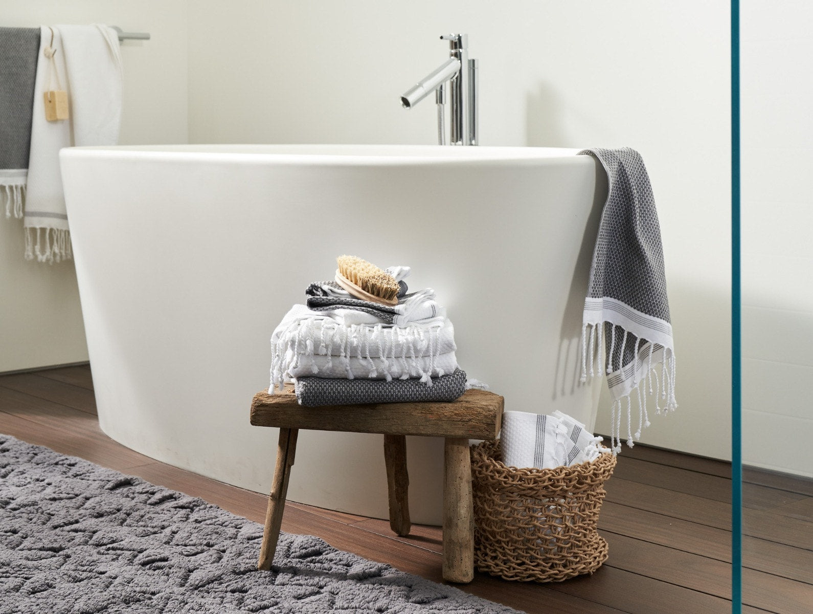 Coyuchi Organic Cotton Mediterranean Towel - stacked beside bath tub #colour_Shadow w/ Deep Pewter Stripes