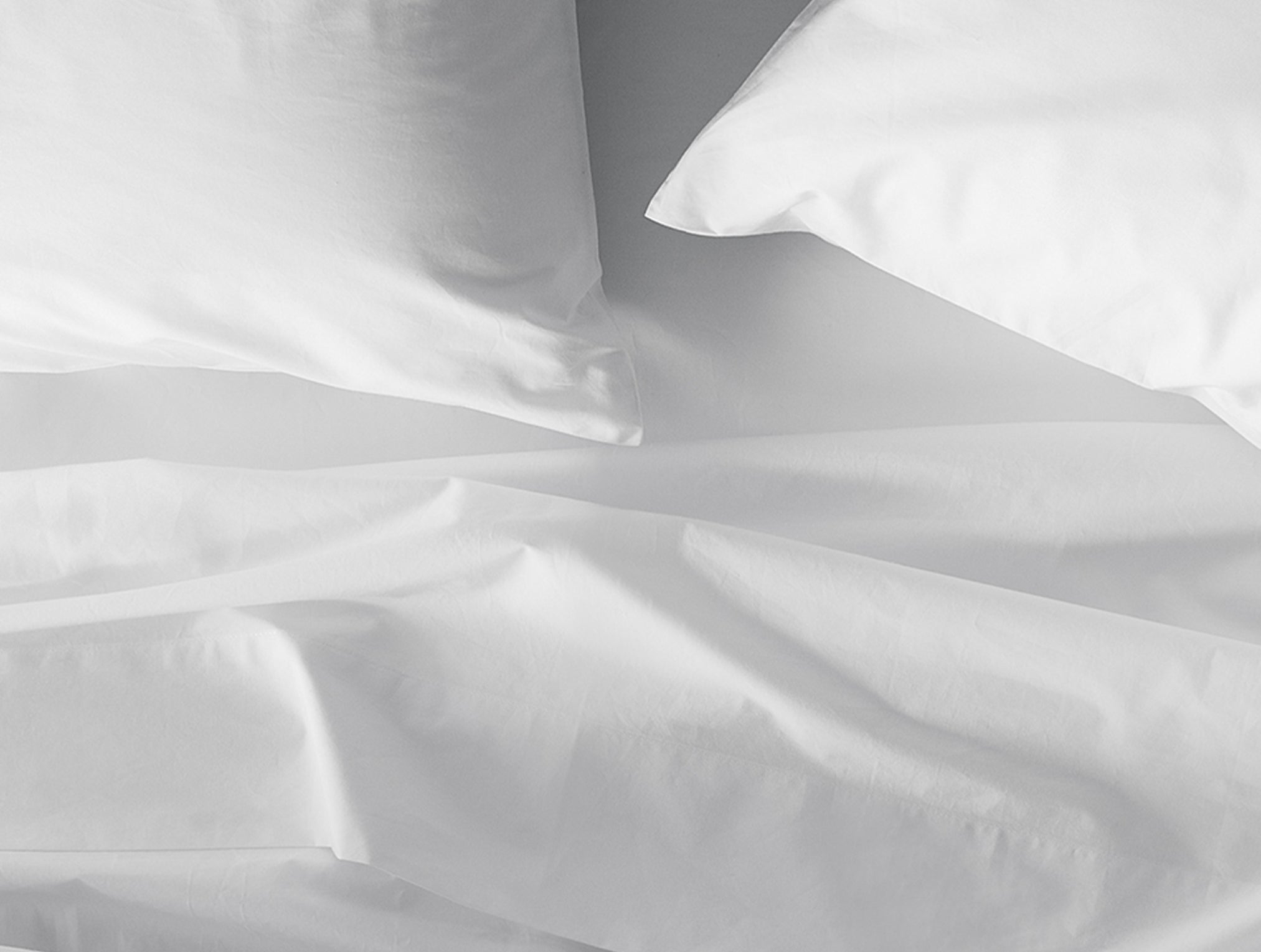 Coyuchi Refined Organic Cotton Percale Sheet Set in Alpine White - close-up detailing smooth texture and weave quality. #colour_alpine white