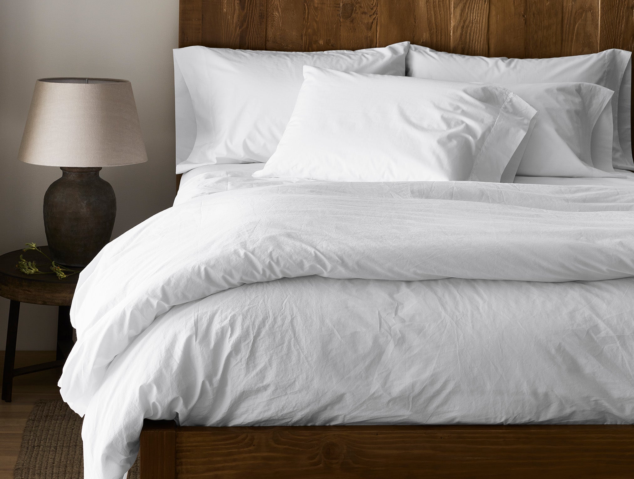 Coyuchi Refined Organic Cotton Percale Sheet Set in Alpine White - made bed with natural wood headboard and frame. #colour_alpine white