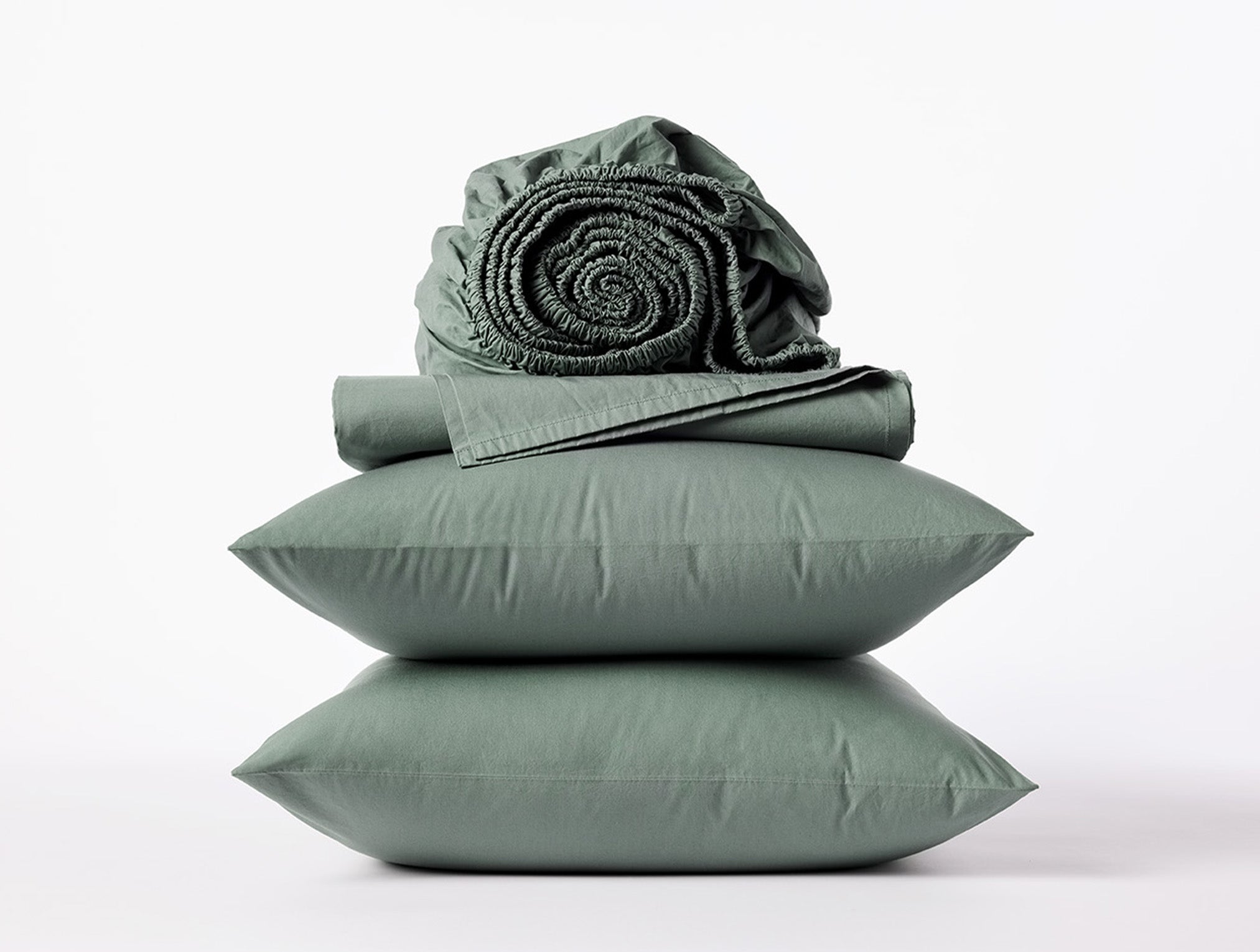 Coyuchi Refined Organic Cotton Percale Sheet Set in Juniper – stacked view with pillows and folded sheets. #colour_juniper