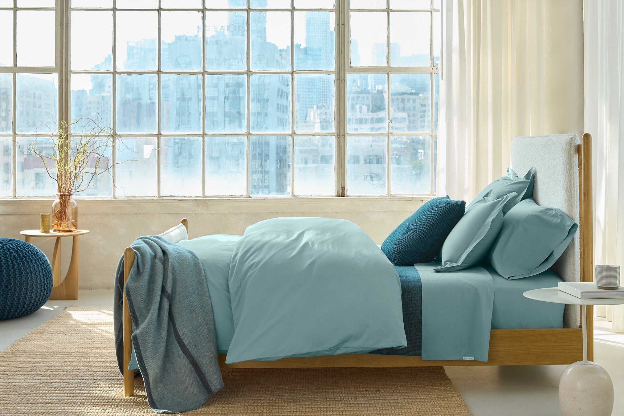 Coyuchi Refined Organic Cotton Percale Sheet Set in Pacific Blue – styled bed underneath a large window, showing the colour in natural light. #colour_pacific blue