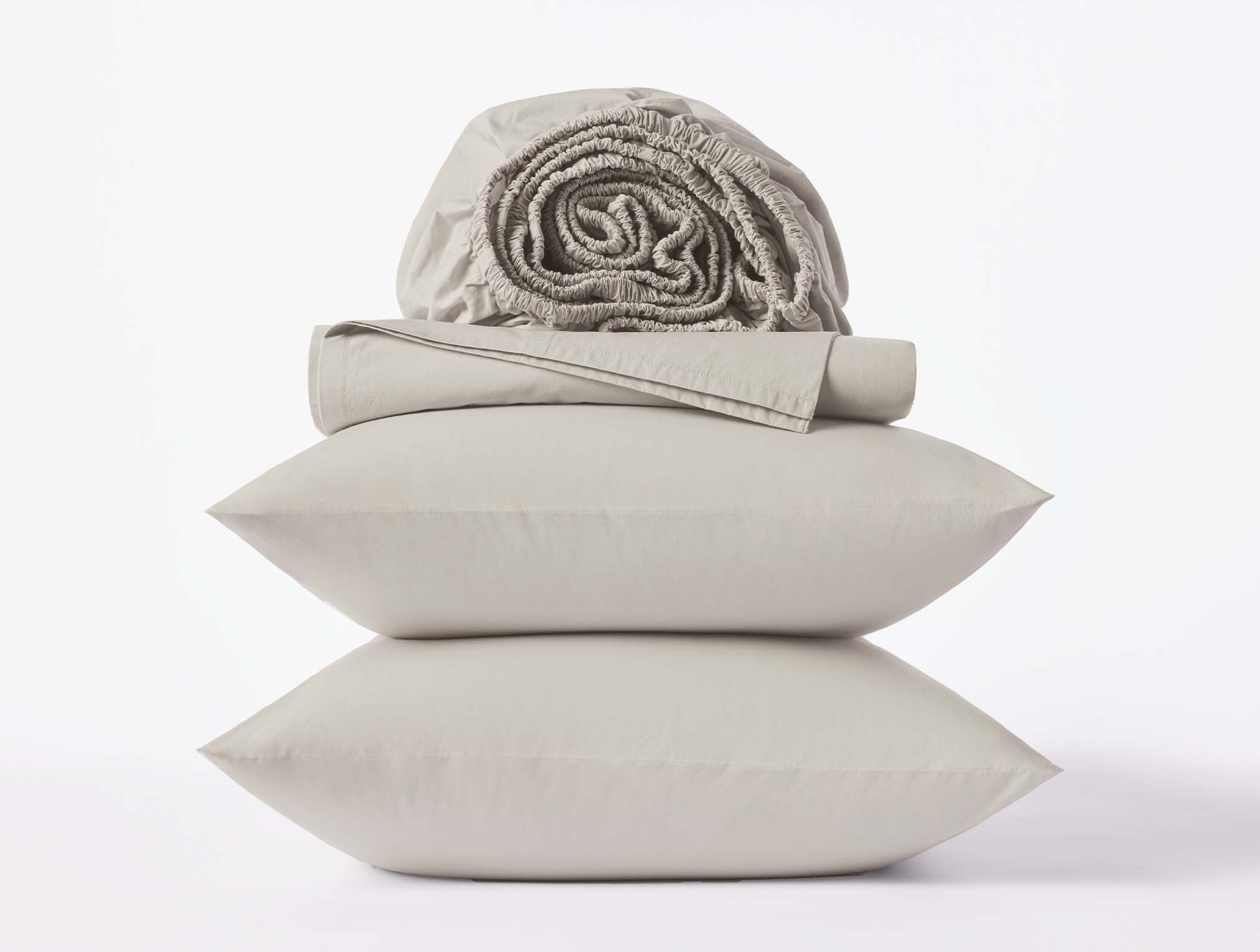 Coyuchi Refined Organic Cotton Percale Sheet Set in Stone – stacked view with pillows and folded sheets. #colour_stone