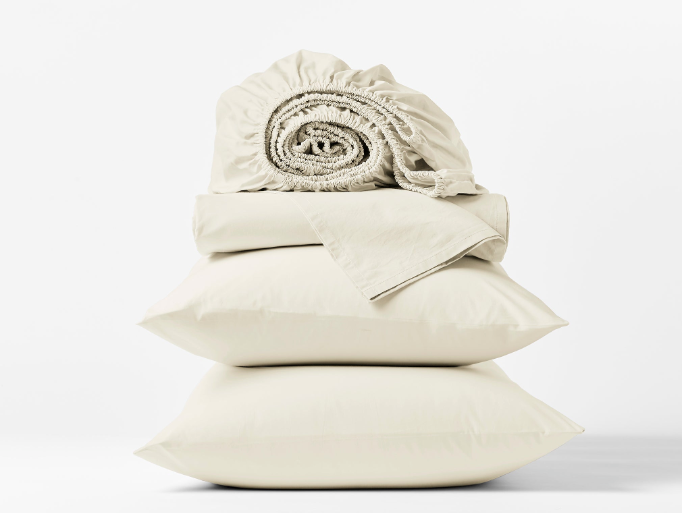Coyuchi Refined Organic Cotton Percale Sheet Set in Undyed – stacked view with pillows and folded sheets. #colour_undyed