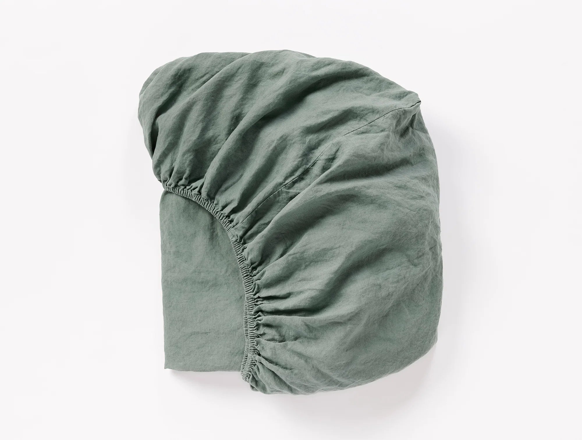 Coyuchi Organic Relaxed Linen Fitted Sheet in Juniper – folded to display elastic in seam. #colour_Juniper