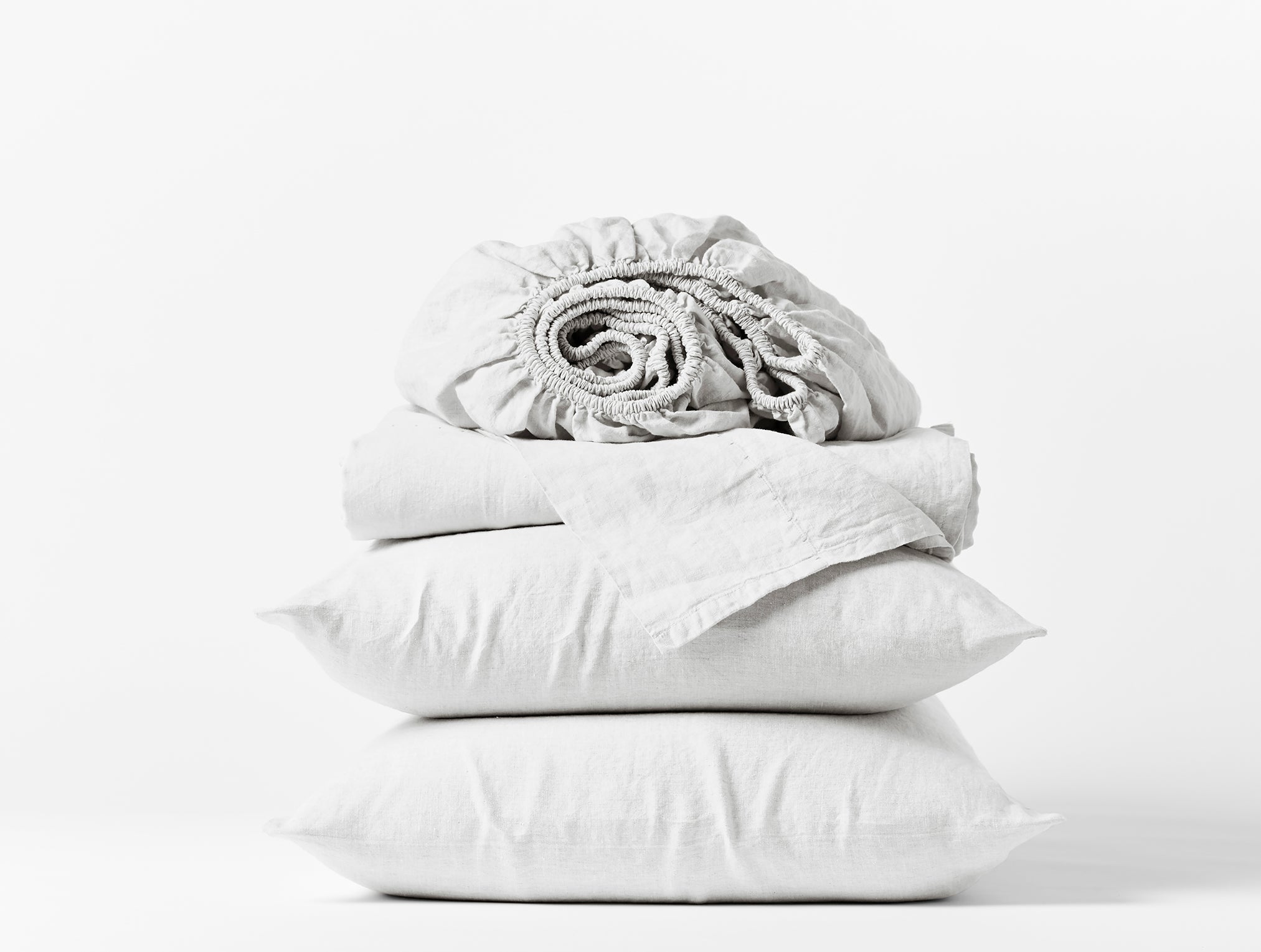 Coyuchi Organic Relaxed Linen Sheet Set in Alpine White – stacked display with pillows and folded sheets. #colour_alpine white