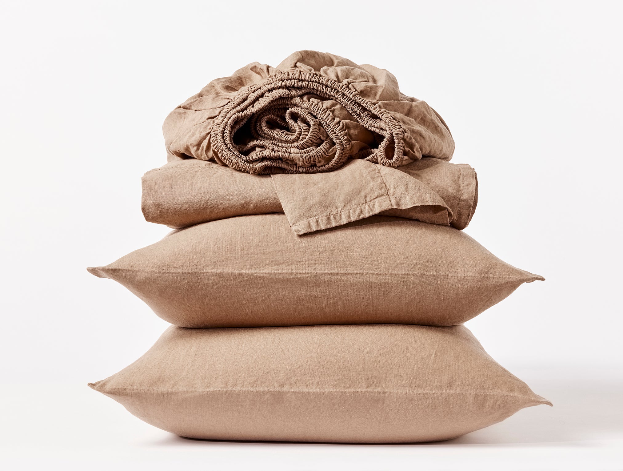 Coyuchi Organic Relaxed Linen Sheet Set in Doe – stacked view with pillows and folded sheets. #colour_doe