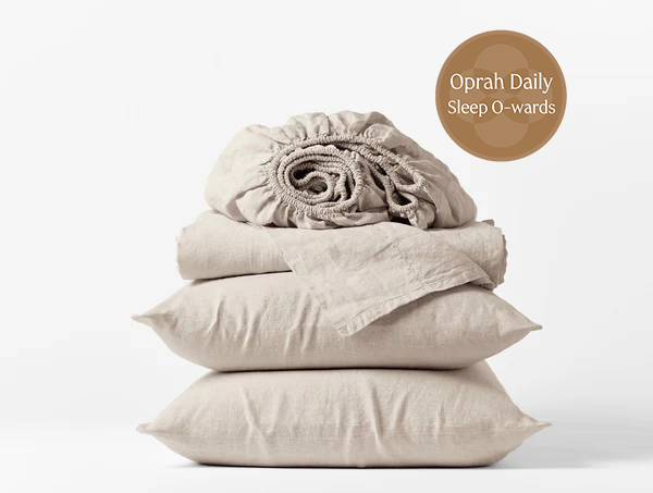 Coyuchi Organic Relaxed Linen Sheet Set in Natural Chambray – stacked view with pillows and folded sheets. #colour_none
