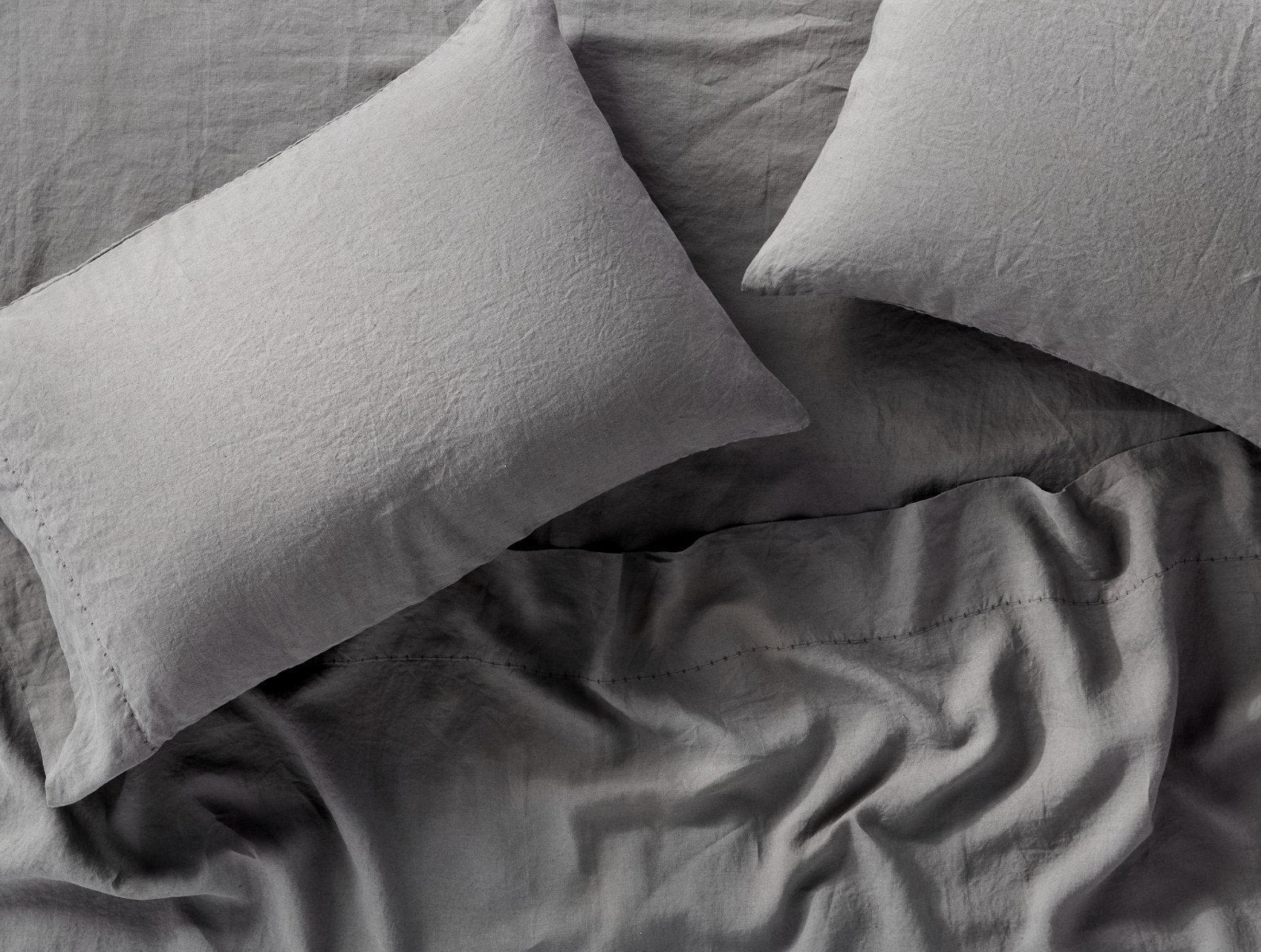 Coyuchi Organic Relaxed Linen Sheet Set in Slate – close-up on texture, highlighting weave and stitching. #colour_slate
