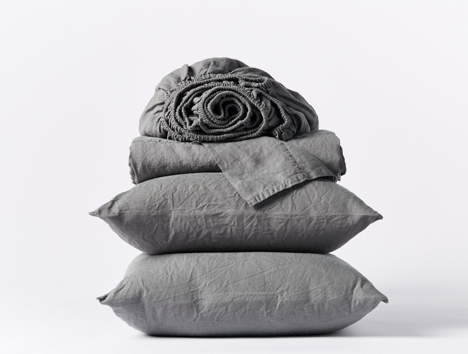 Coyuchi Organic Relaxed Linen Sheet Set in slate – stacked display with pillows and folded sheets. #colour_slate