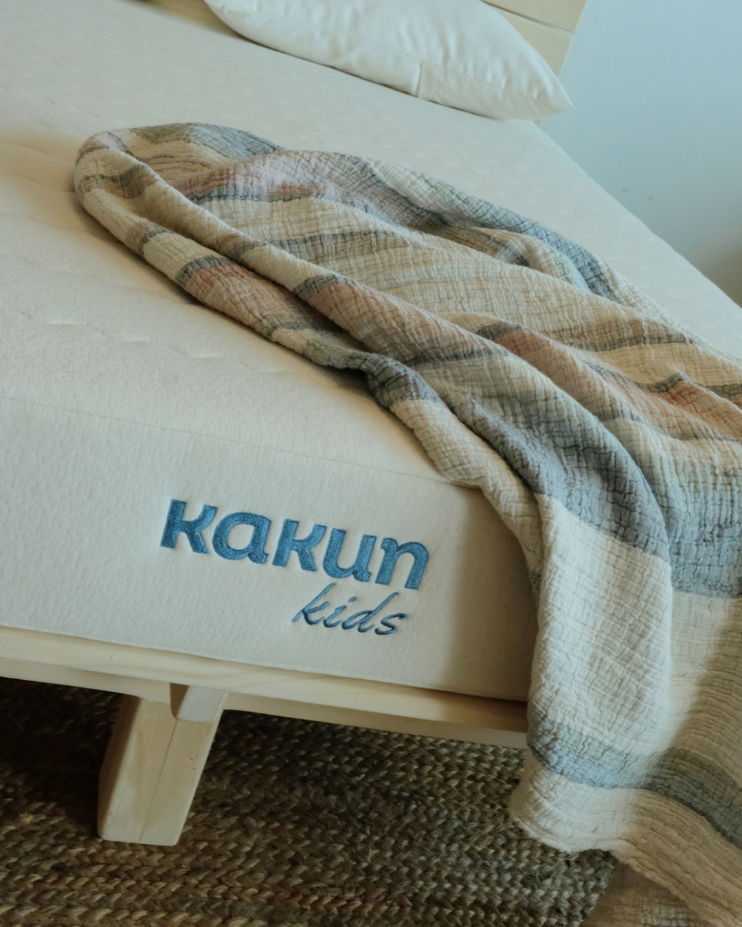 Kakun Organic Latex Kids Mattress - close up of logo with throw blanket on mattress