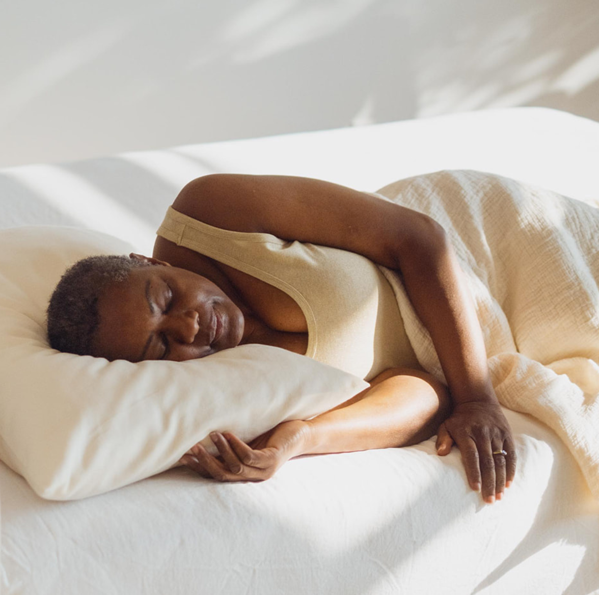Kakun Organic Pillow - model laying on bed with natural light