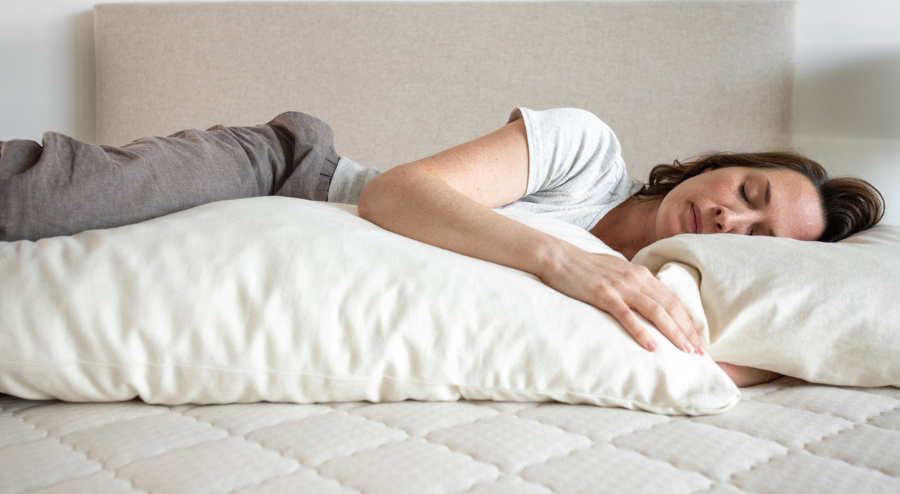 Kakun Organic Wool Body Pillow - side view of woman sleeping with pillow, showing alignment of hips and shoulders.