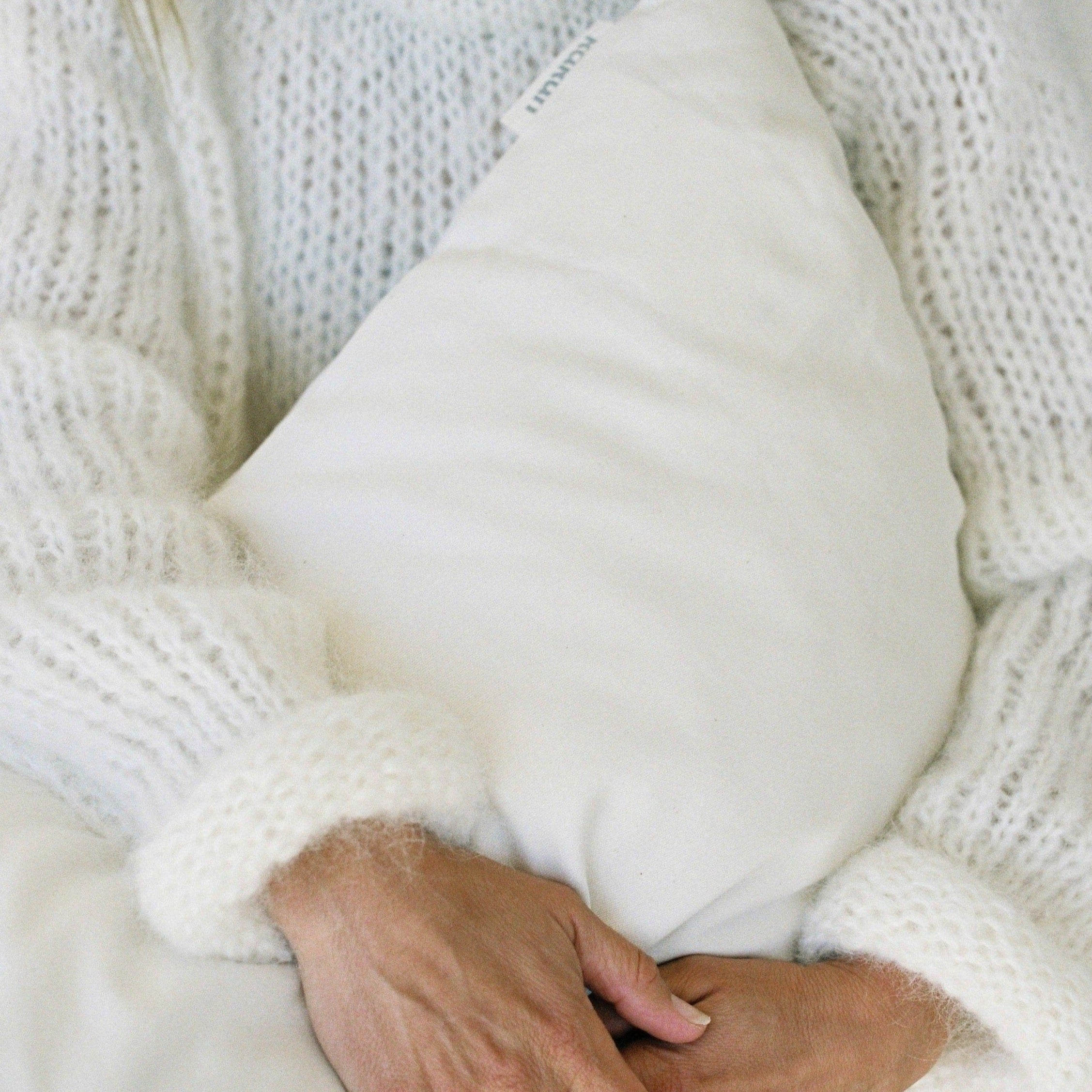 Kakun Organic Wool Pillow - pillow held in arms, showing soft and cozy quality.