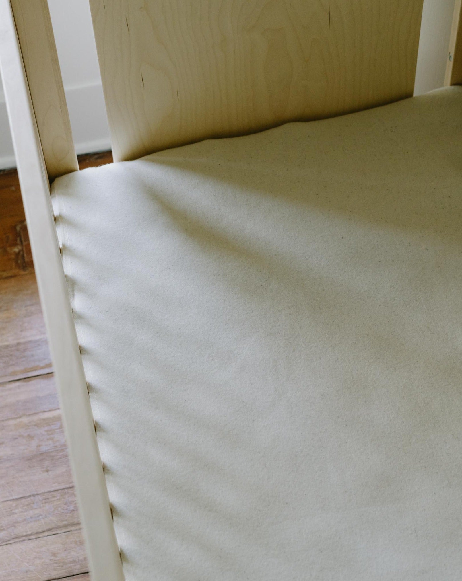 Kakun Premium Eco Wool Puddle Pad - view of top of pad on a mattress in crib