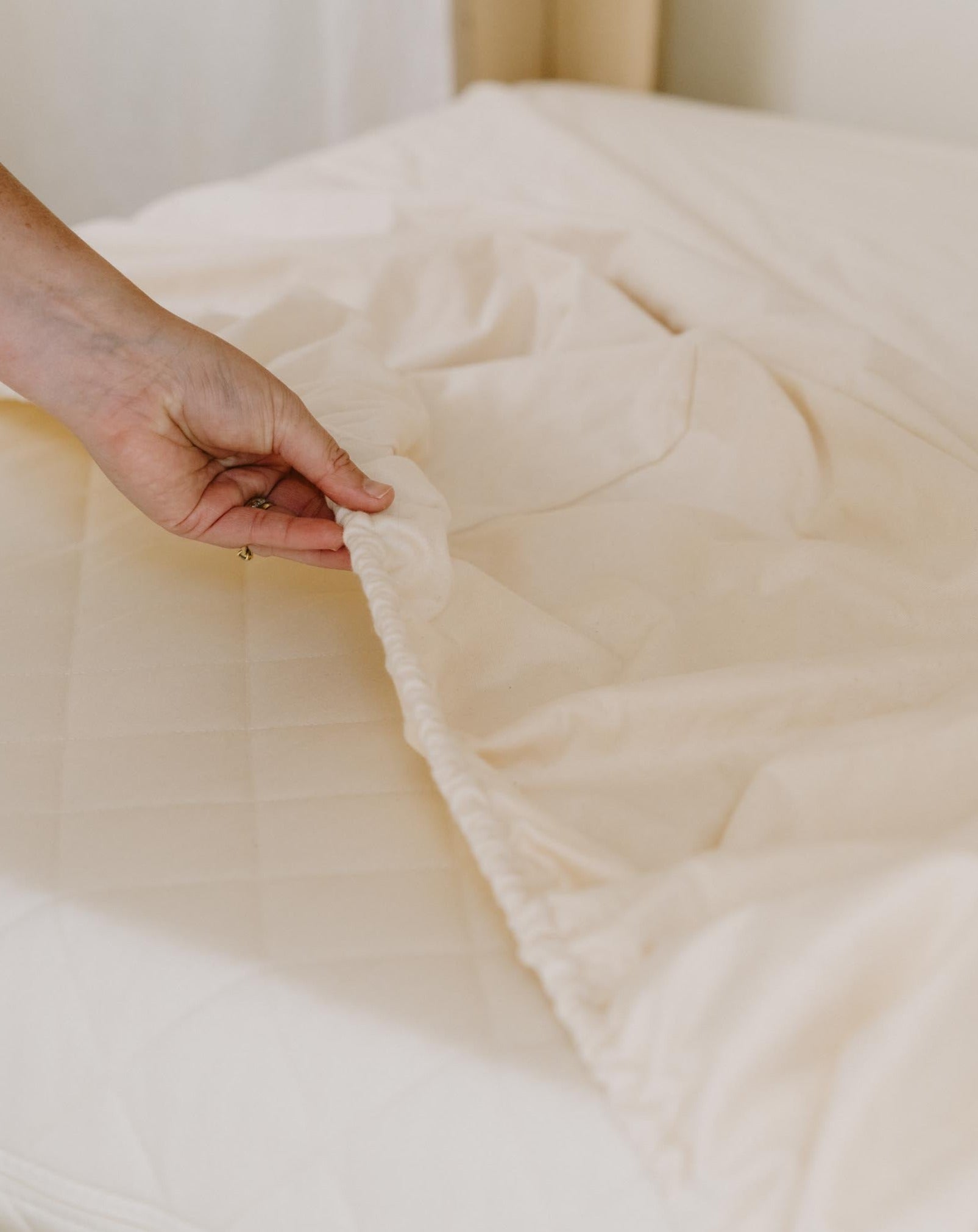 Kakun Waterproof Mattress Protector - hand grabbing elastic edge