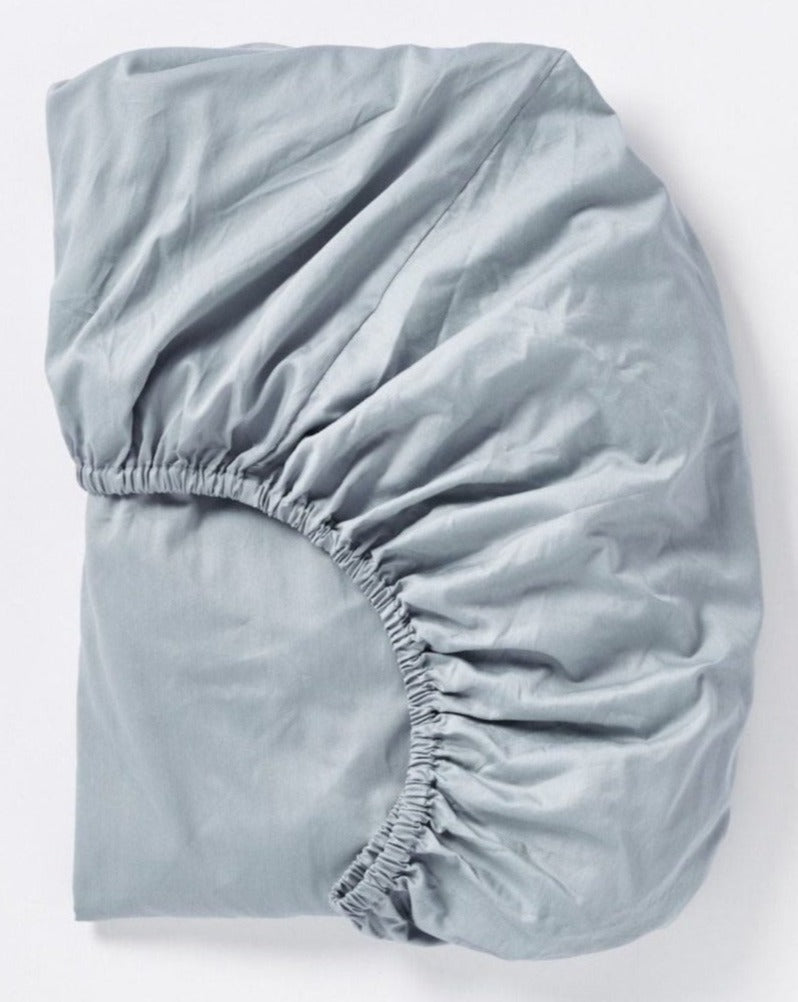Coyuchi Cloud Soft Organic Sateen Fitted Sheet in Pale Ocean – folded, displaying elastic in seam. #colour_pale ocean