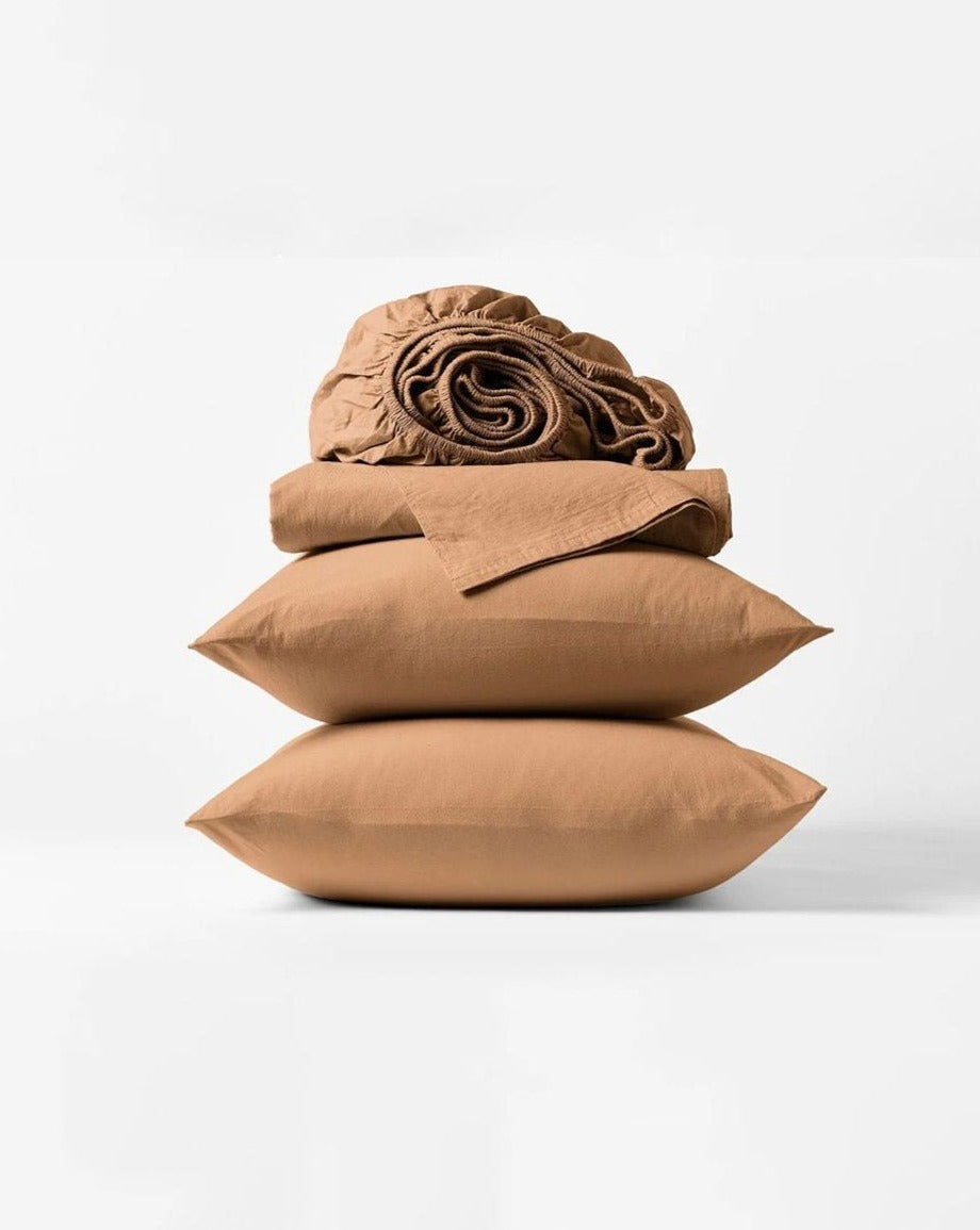 Coyuchi Organic Crinkled Percale Sheet Set in Ginger – stacked display with pillows and folded sheets. #colour_ginger