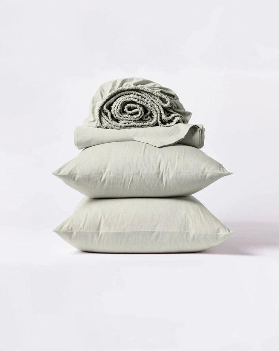 Coyuchi Organic Crinkled Percale Sheet Set in Laurel Chambray – stacked display with pillows and folded sheets. #colour_laurel chambray