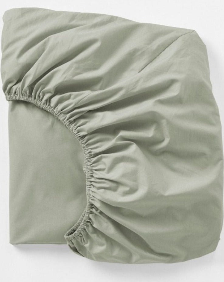 Coyuchi Refined Organic Percale Fitted Sheet in Laurel – folded, displaying elastic in seam. #colour_laurel