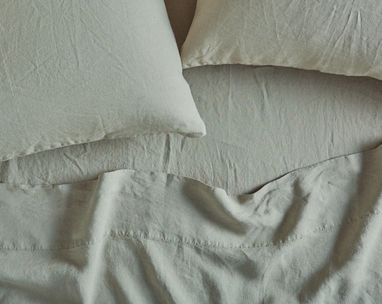 Coyuchi Organic Relaxed Linen Fitted Sheet in Laurel – detail shot of relaxed texture and quality of stitching along flat sheet. #colour_laurel