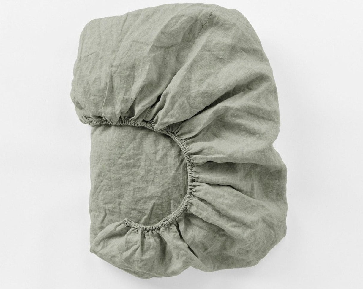 Coyuchi Organic Relaxed Linen Fitted Sheet in Laurel – folded to display texture and elastic in seam. #colour_laurel