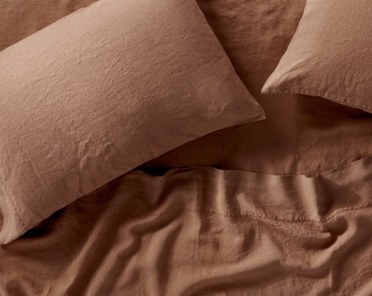 Coyuchi Organic Relaxed Linen Fitted Sheet in Redwood – detail shot of linen texture and weave on pillowcases and sheets. #colour_Redwood