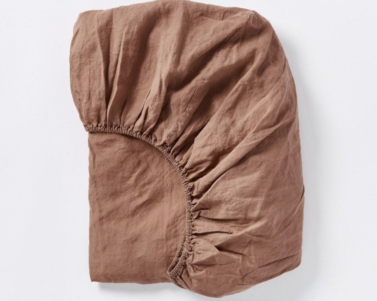 Coyuchi Organic Relaxed Linen Fitted Sheet in Redwood – folded to display elastic in seam. #colour_Redwood