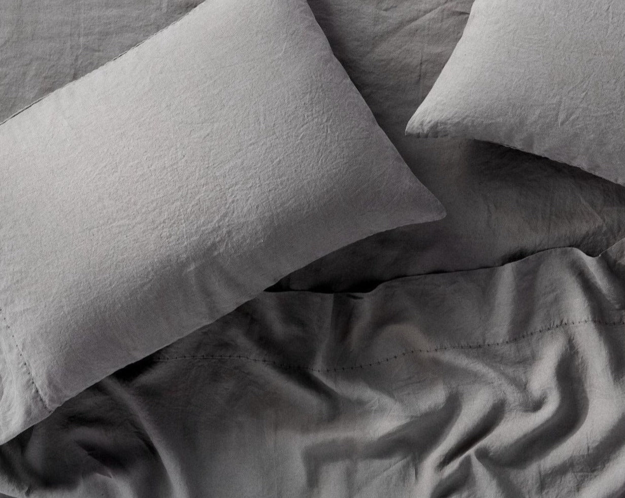 Coyuchi Organic Relaxed Linen Fitted Sheet in Slate – close-up of linen texture on pillowcases, on top of made bed. #colour_Slate