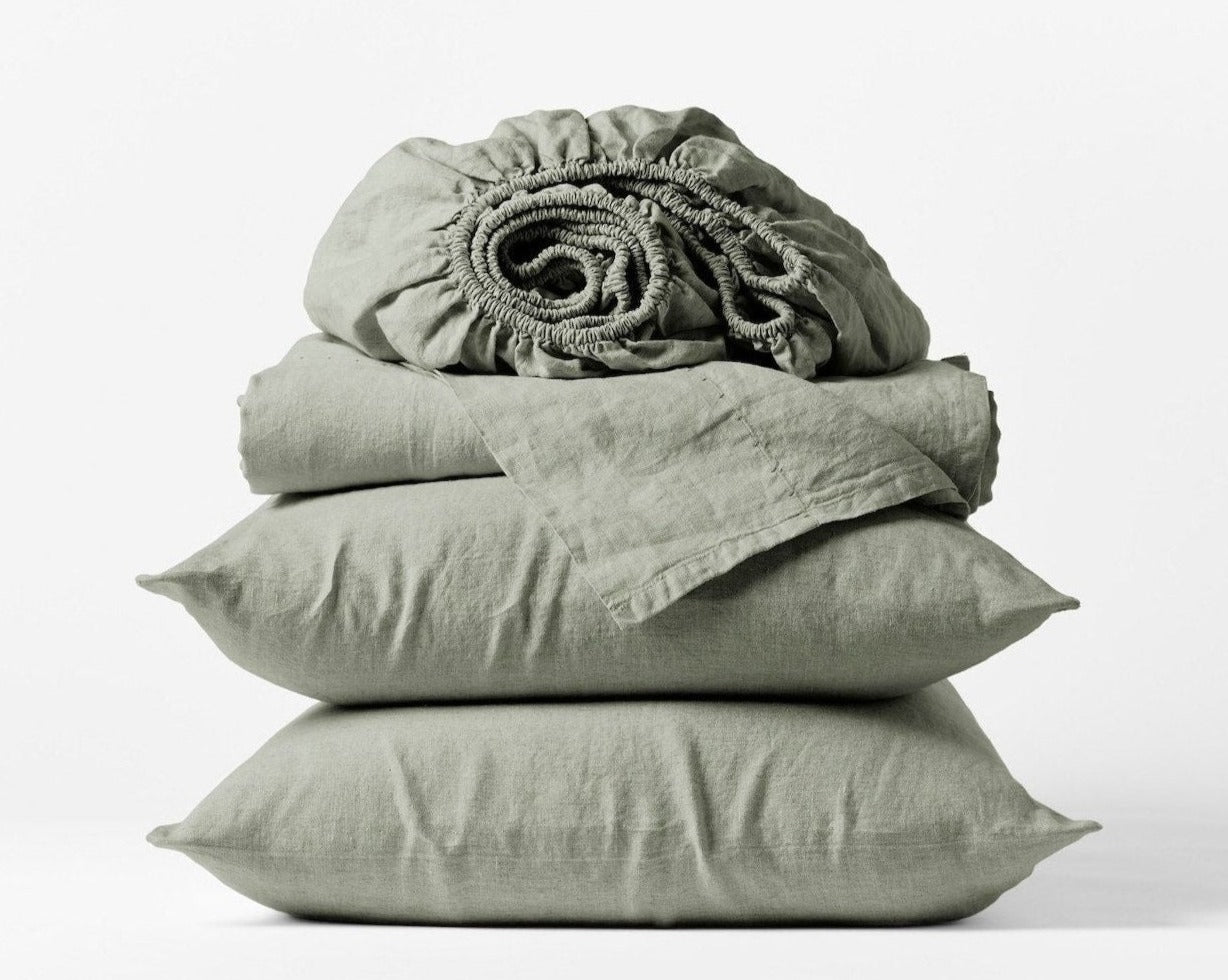 Coyuchi Organic Relaxed Linen Sheet Set in Laurel – stacked display with pillows and folded sheets. #colour_laurel